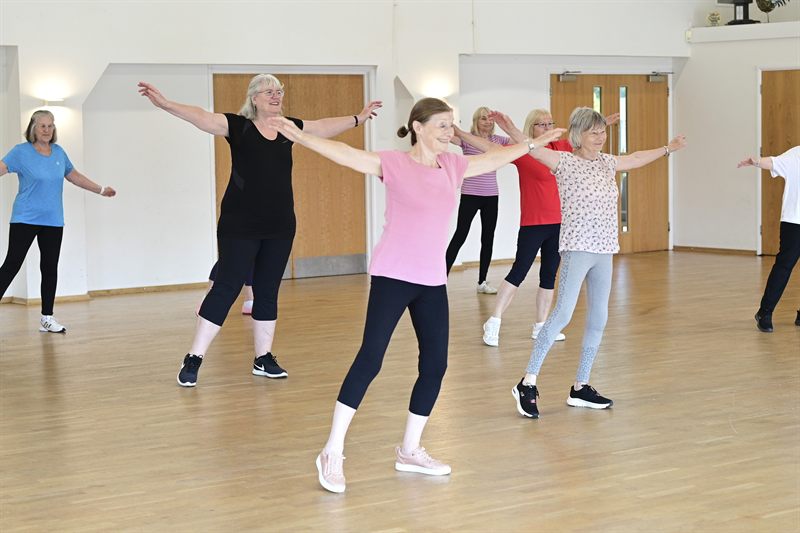A group taking part in a seated and standing aerobics class
